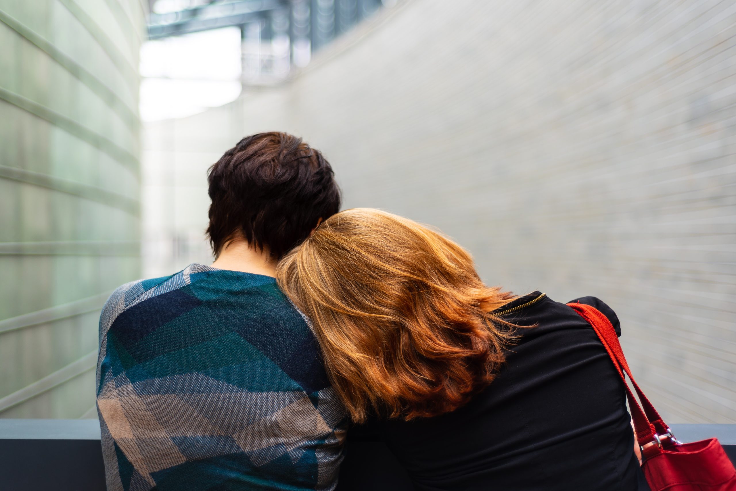 rear view of two young women sitting on bench